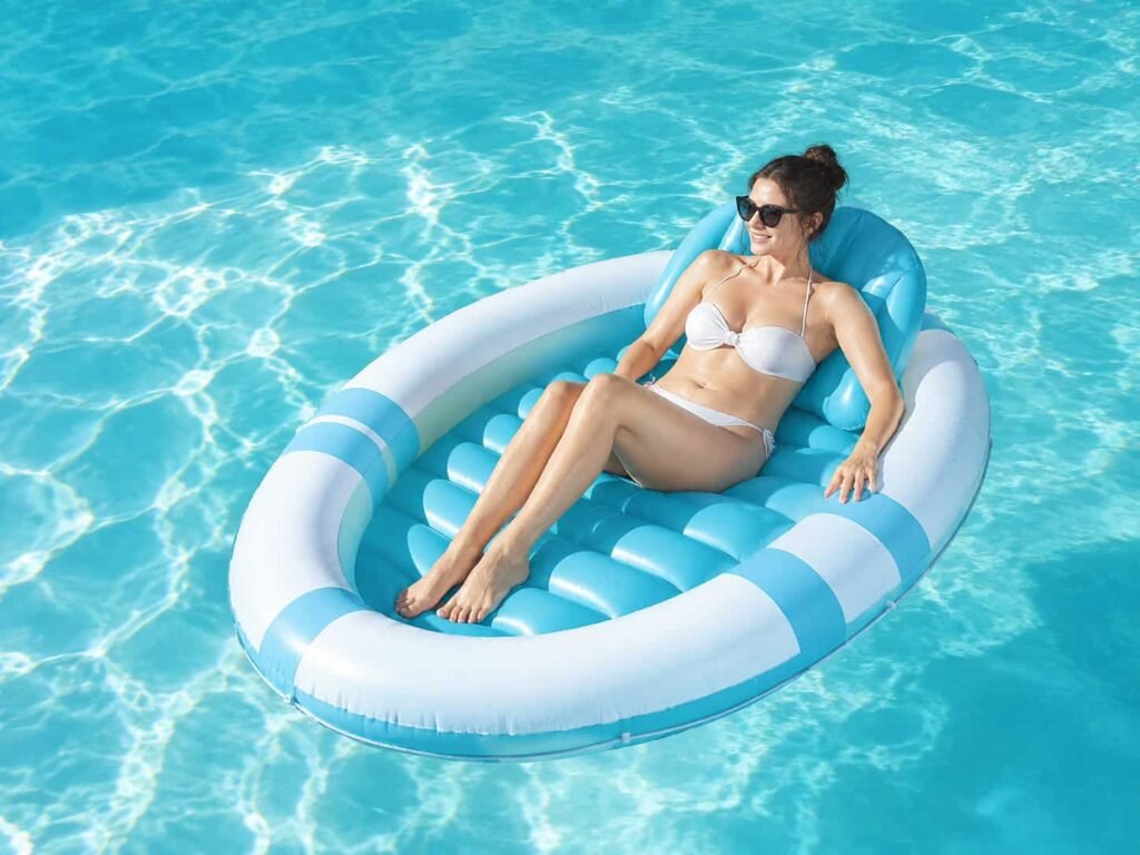 Round inflatable tanning pool lounger with cushioned rim and removable pillow